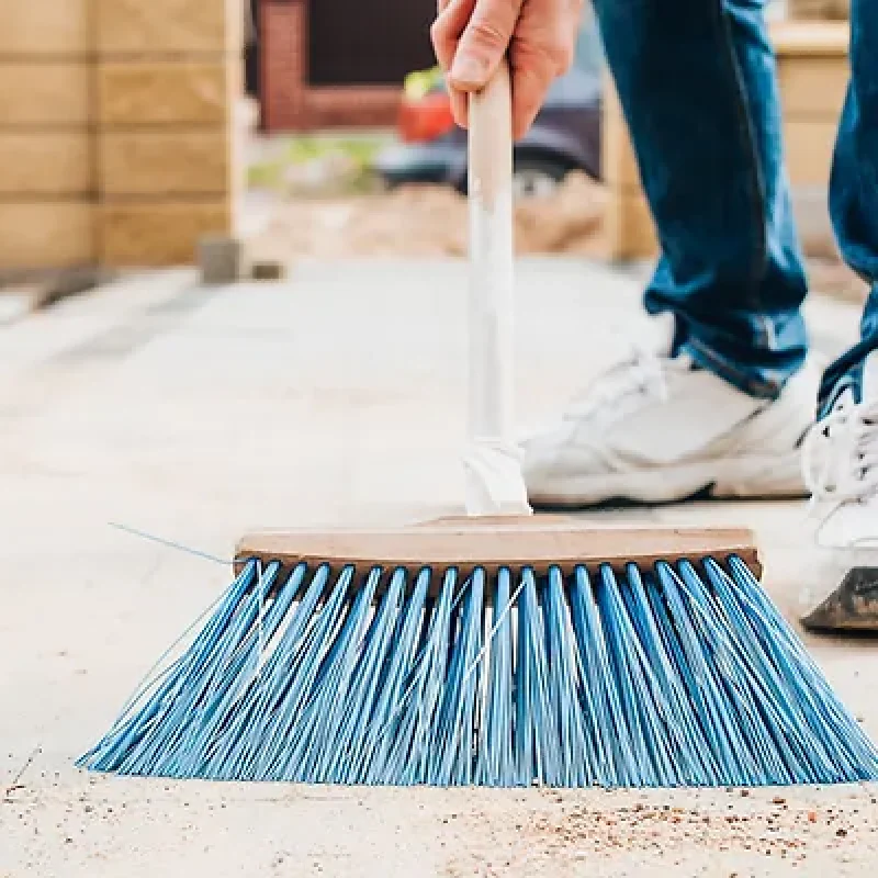 A man with a brush sweeps the paving slabs on the path near the house – general cleaning o A man with a brush sweeps the paving slabs on the path near the house - general cleaning o
